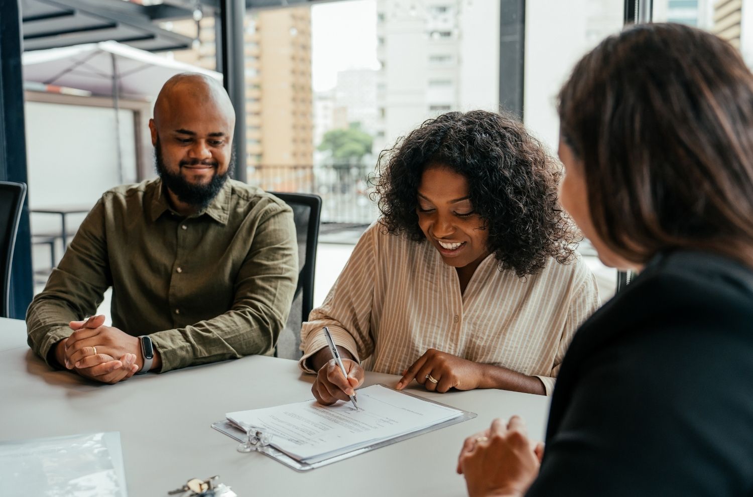 Couple signing paperwork with real estate agent 