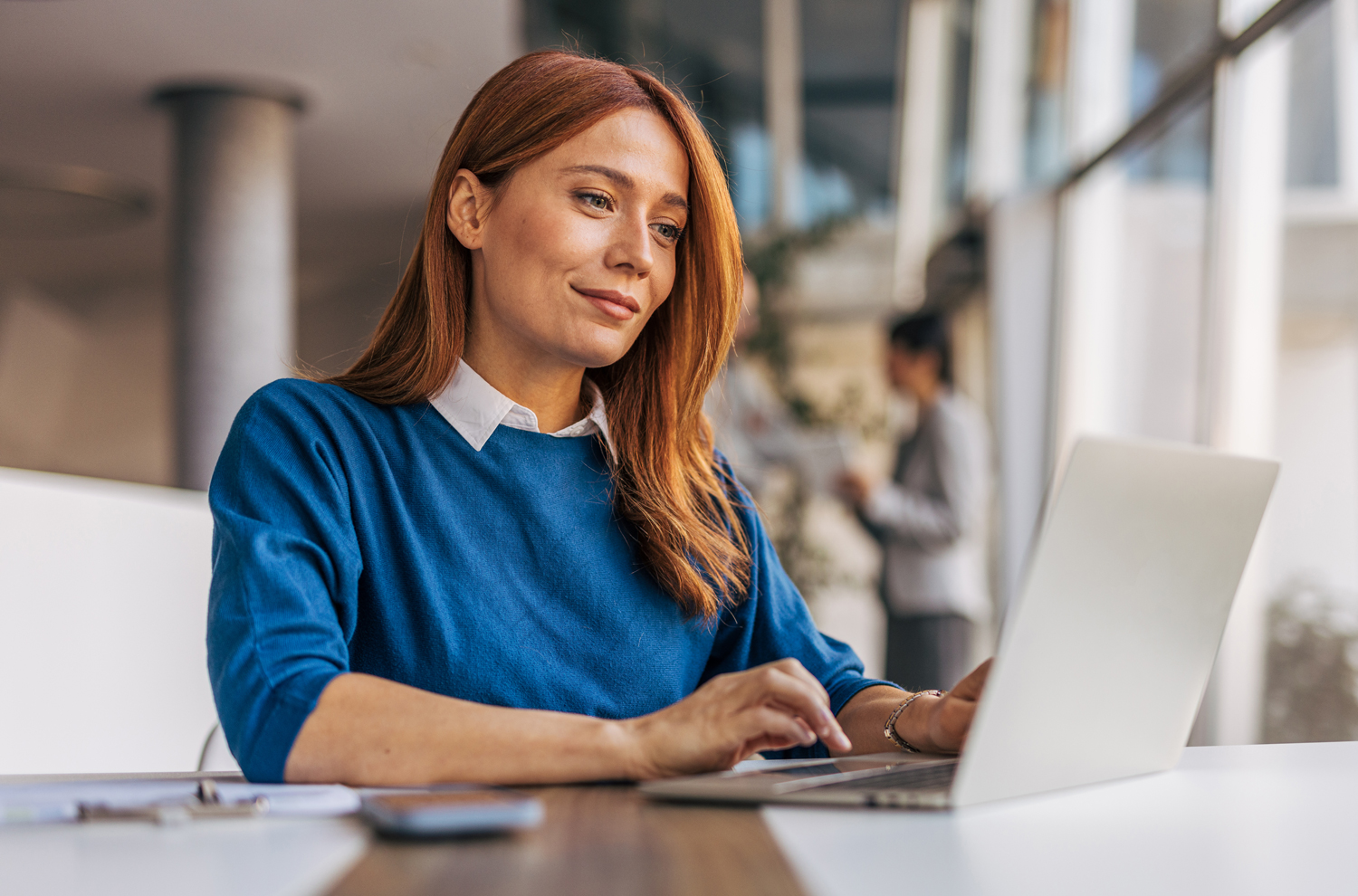 Businesswoman at desk looking at emails on laptop computer