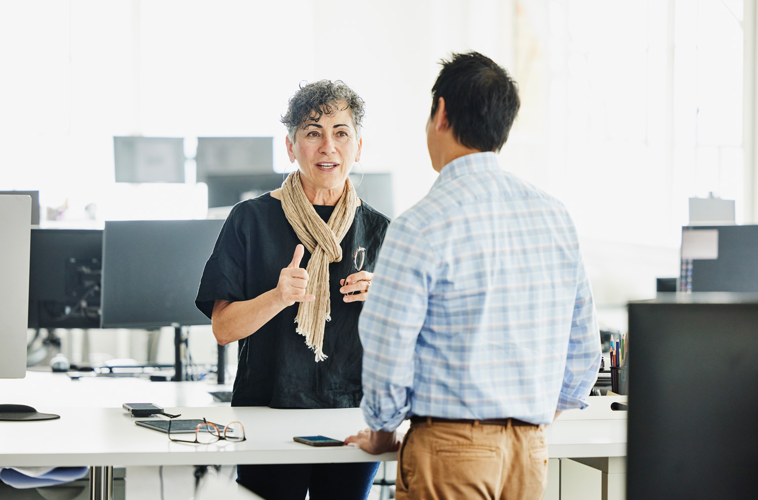 Two businesspeople conversing over a standing desk