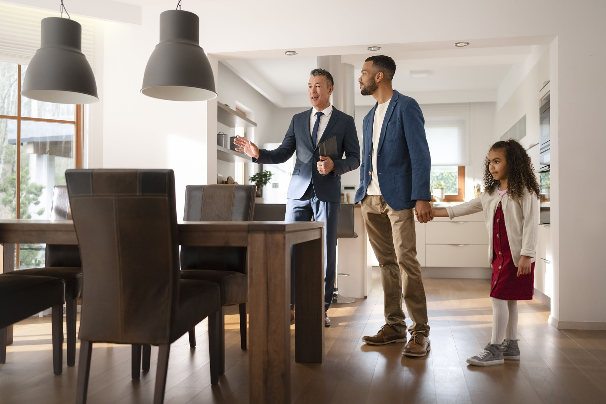 A realtor showing a dad and daughter around a kitchen.