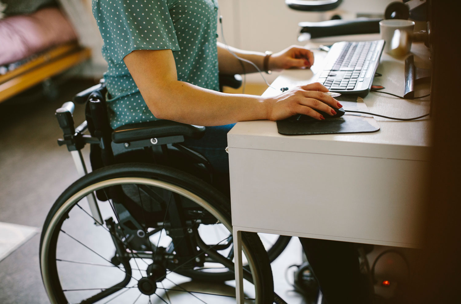 Woman in wheelchair typing on computer at home