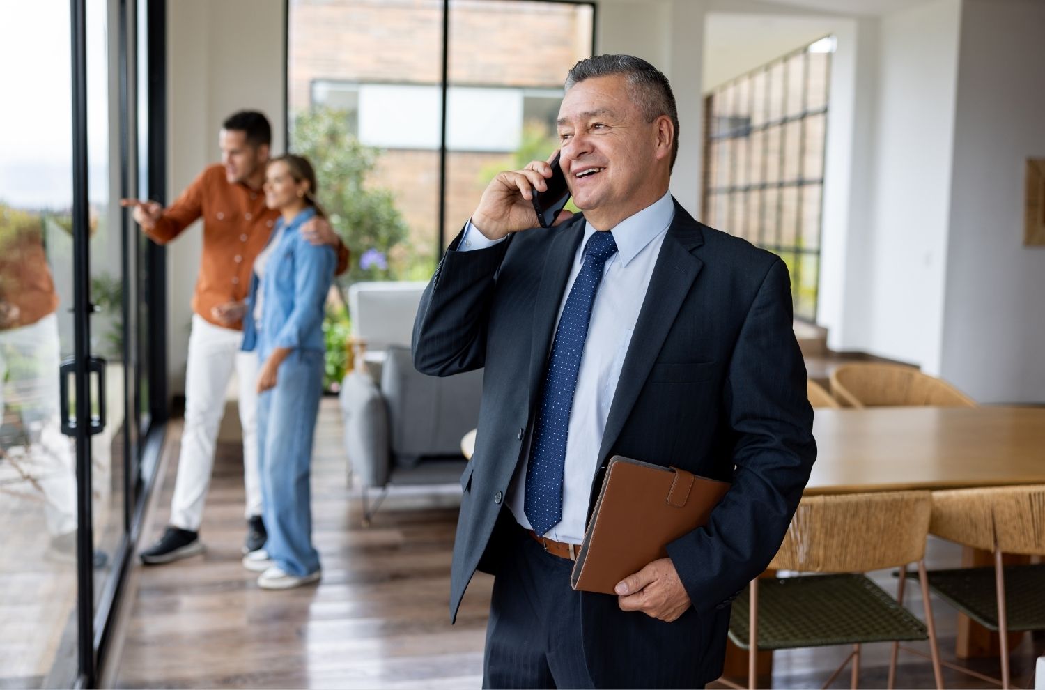 Realtor speaking on phone with homebuyers in background