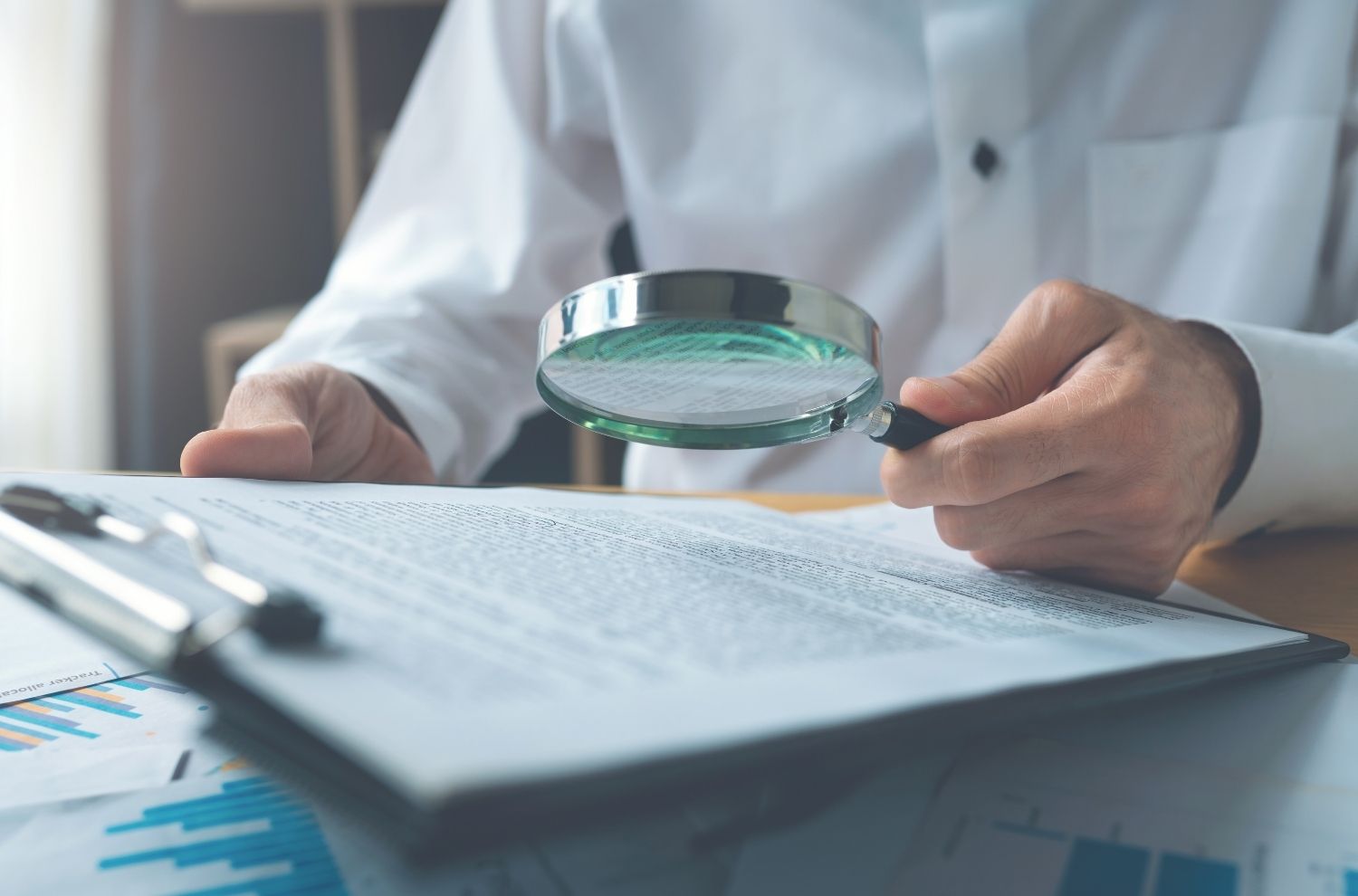 Businessman looking at contracts through magnifying glass