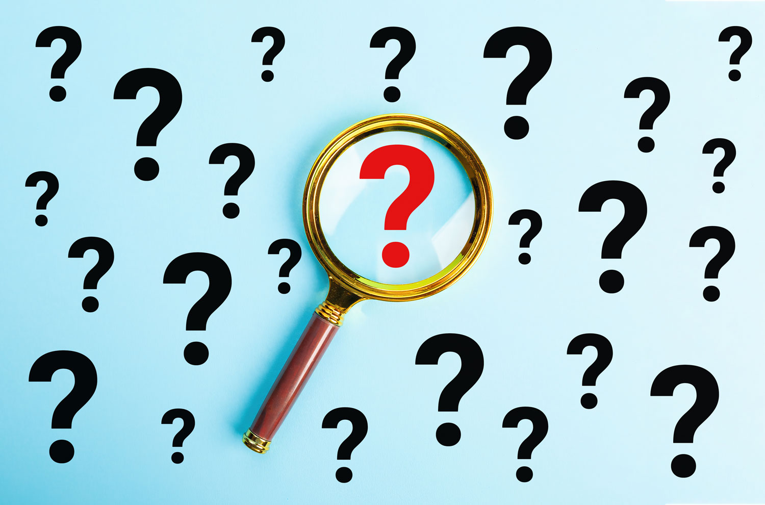 Magnifying glass showcasing a question mark against display full of question marks