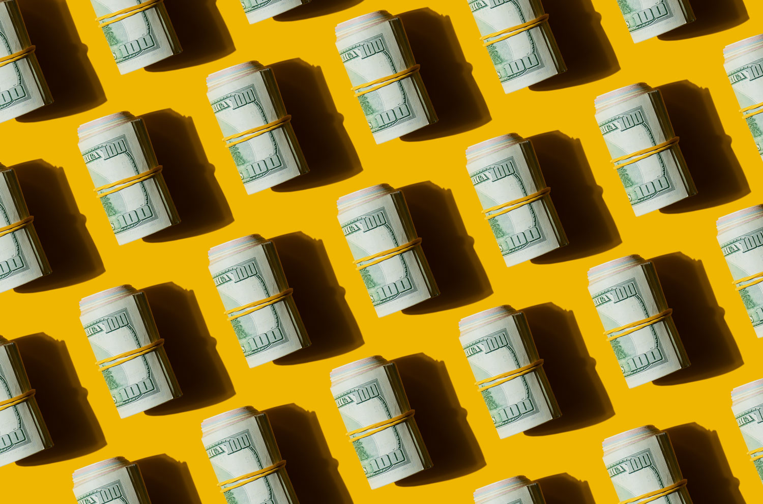 Rolls of U.S dollar bills sitting on a yellow table