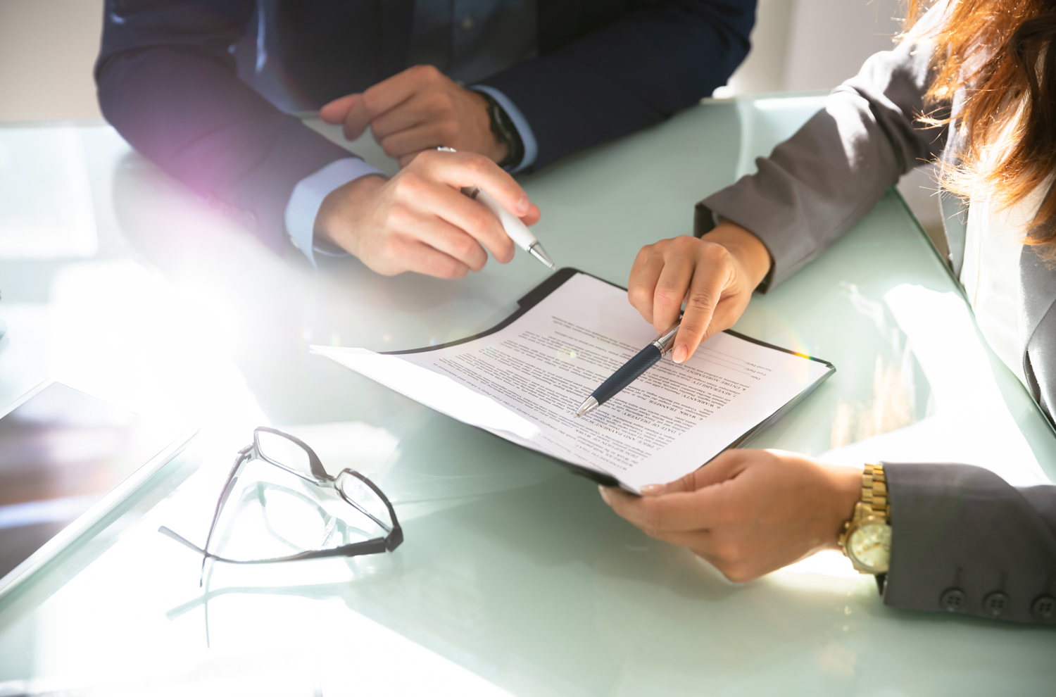 Aerial view of two people reviewing a contract on board room desk
