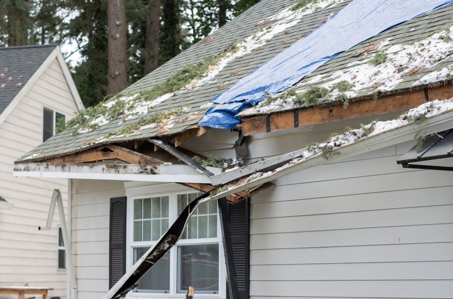Damaged gutter and roof on home exterior after storm