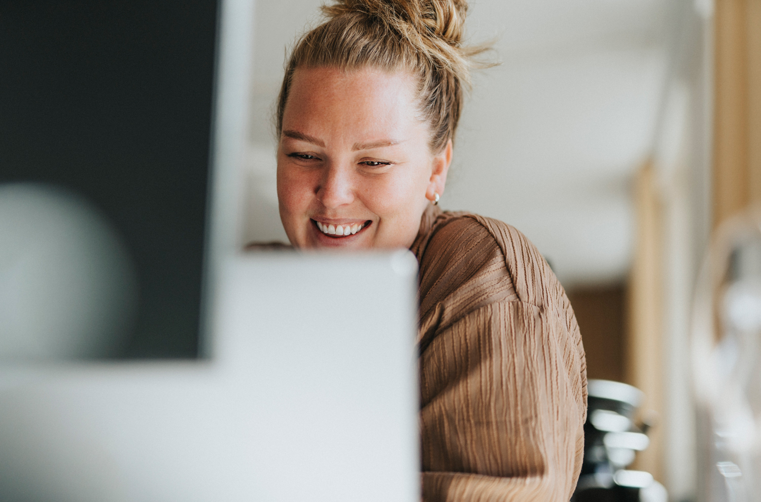 Woman smiling while looking at desktop computer