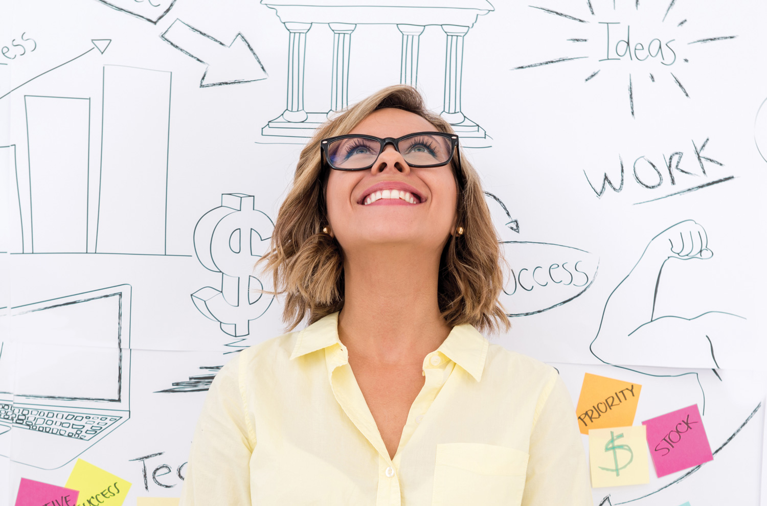 Smiling businesswoman by brainstorms on chalkboard