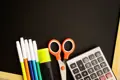 Scissors, markers an other school supplies sitting against small chalkboard