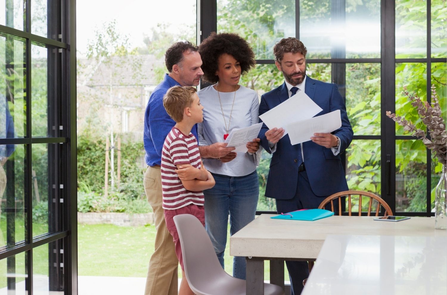 Family standing with real estate agent in kitchen reviewing paperwork
