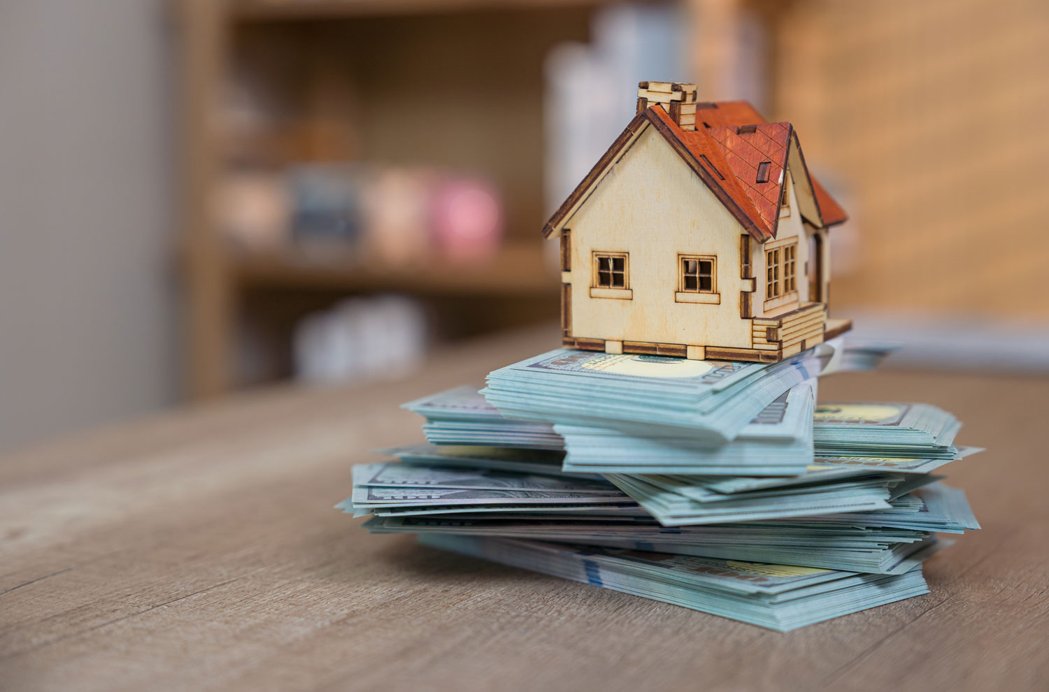 Model house sitting atop stacks of U.S. dollar bills