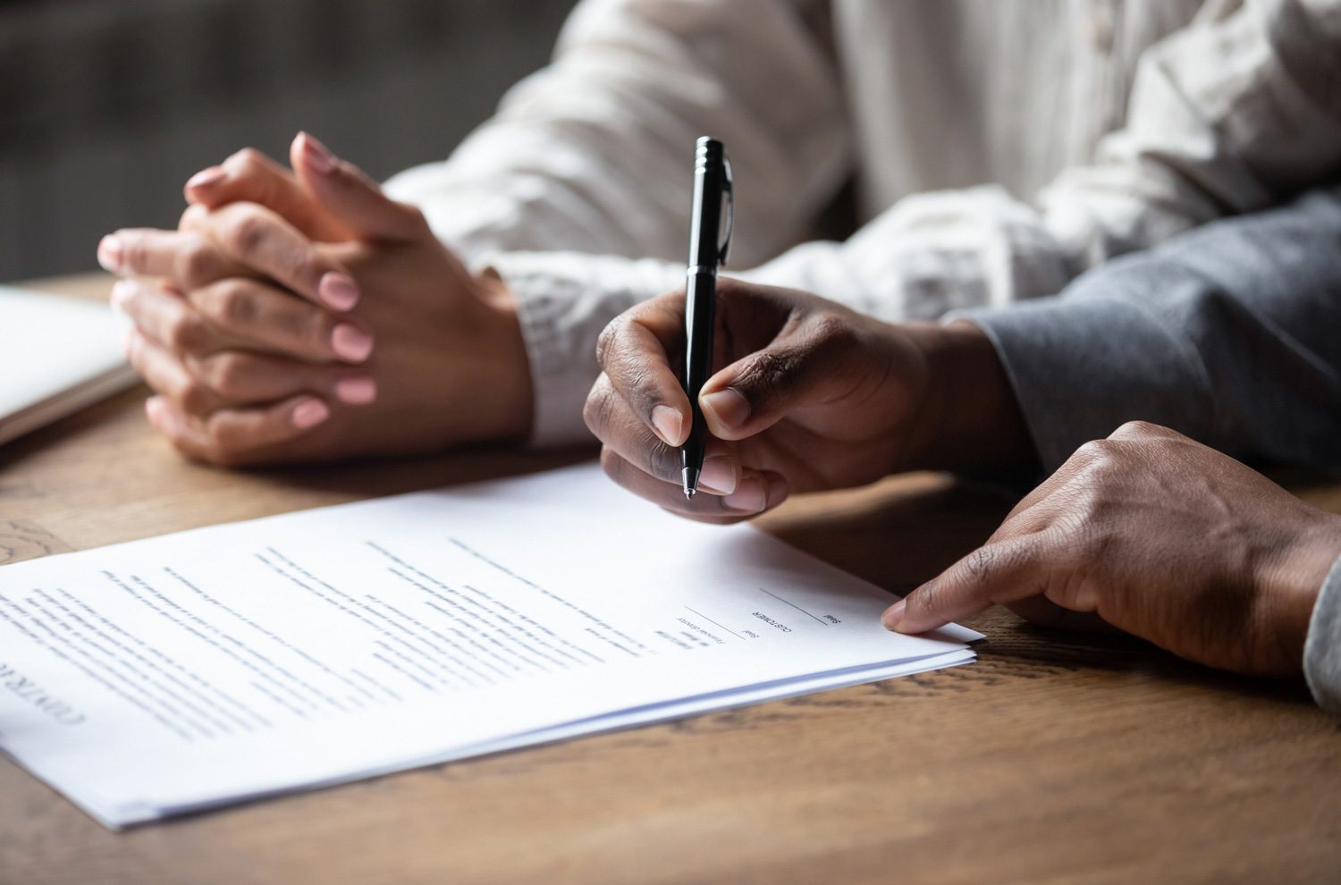 Two sets of hands closeup signing legal documents