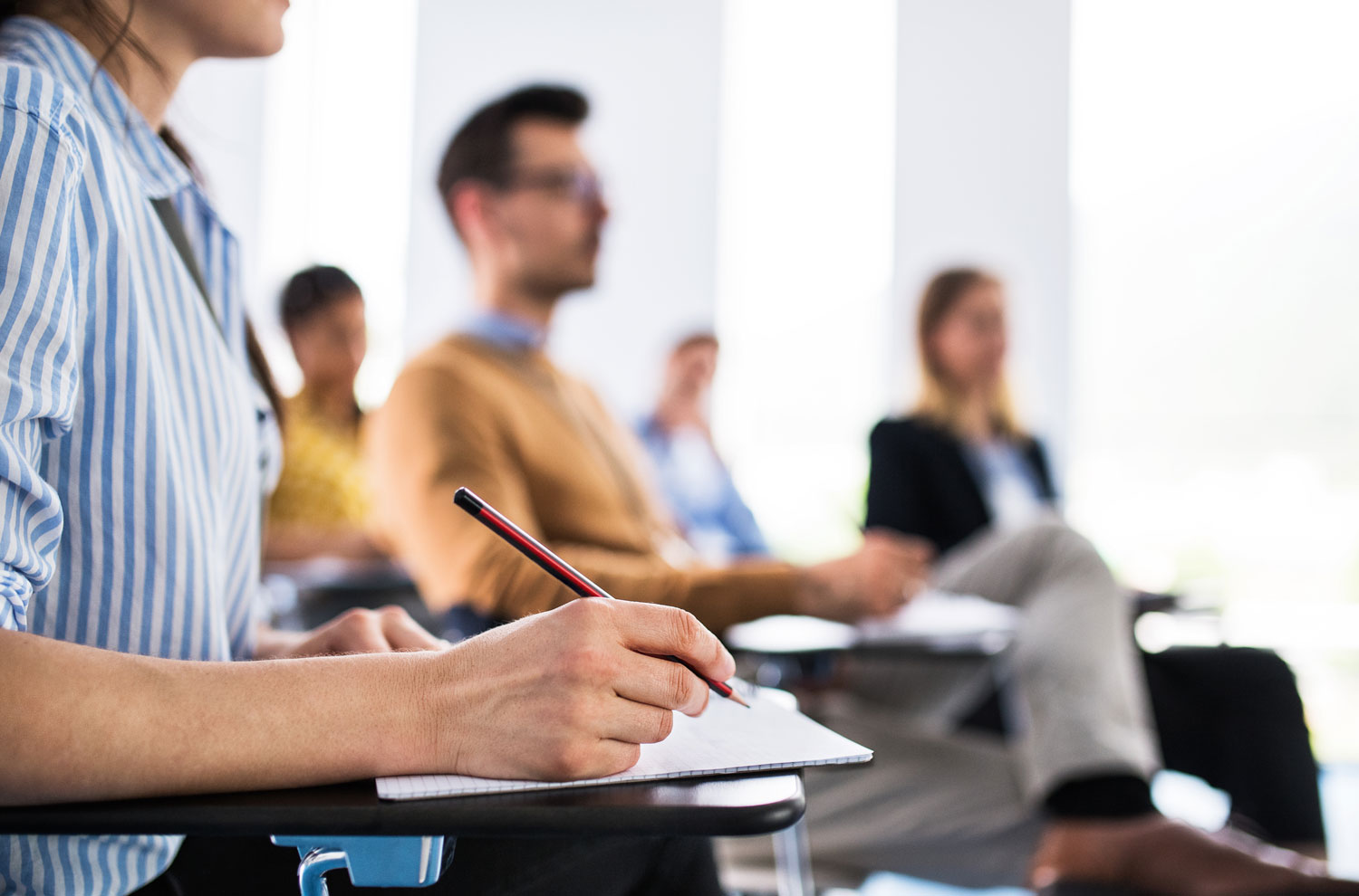 Closeup of student taking notes in notepad during an educational lecture