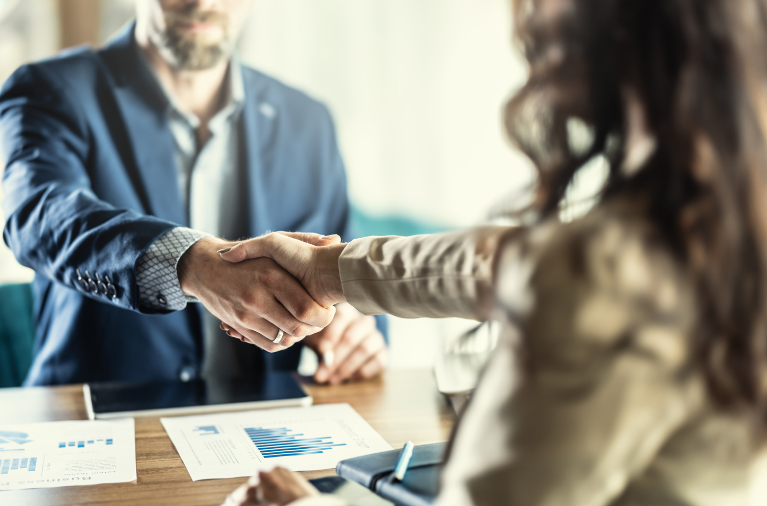 Two businesspeople shaking hands at executive desk