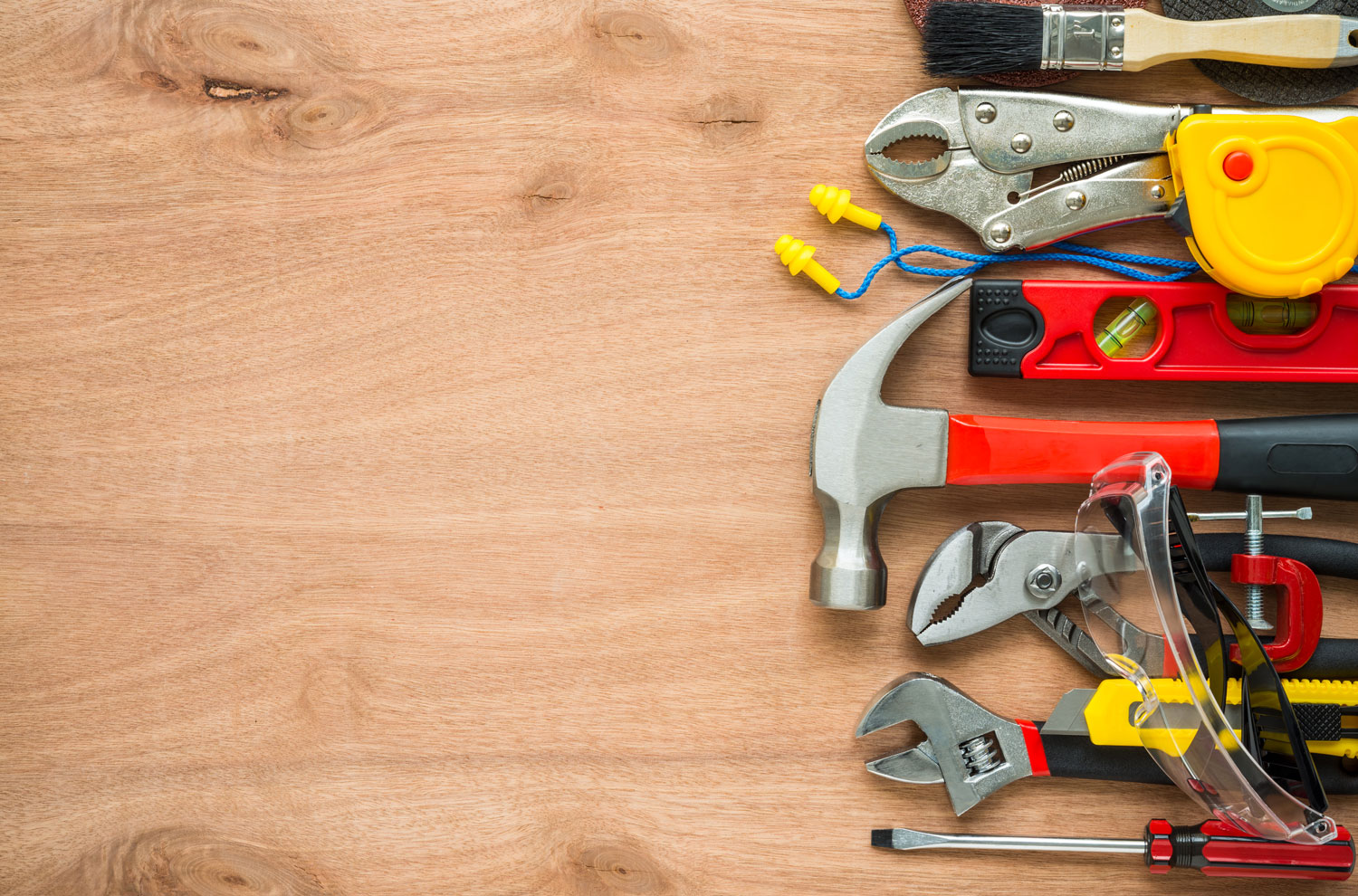 Hammer, wrench and other tools sitting on top of a wooden desk